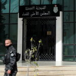 Police officer walks outside the Supreme Judicial Council building during a protest in Tunis