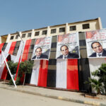 A man walks in front of polling stations covered from outside by Egyptian flags and posters of Egypt’s President Abdel Fattah al-Sisi during the preparations for tomorrow’s presidential election in Cairo